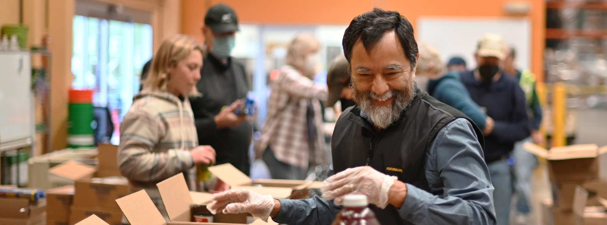 Man distributing food from boxes while smiling at river city food bank